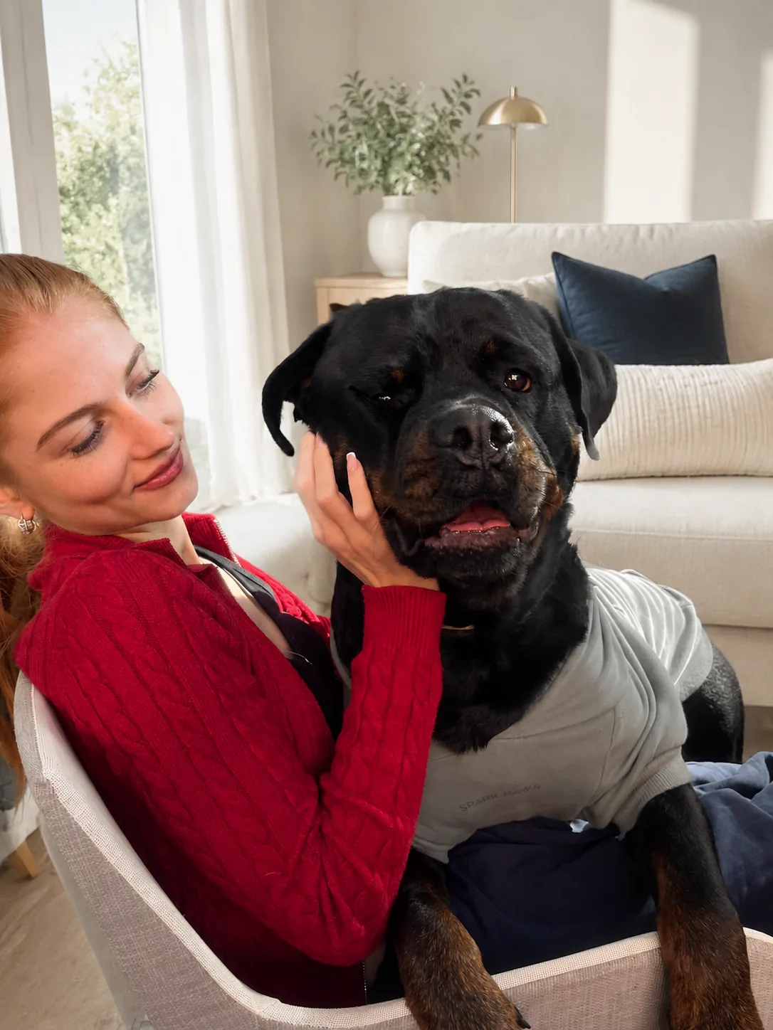 A woman gently holding the face of her Rottweiler